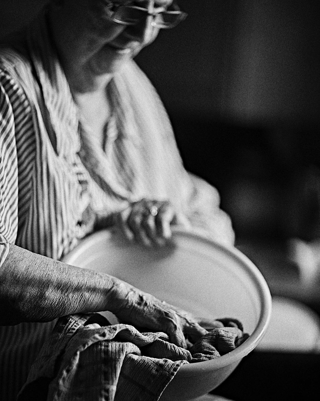 Monochrome portrait of an elderly woman washing clothes in a basin, captured by Annie Edmonds in Los Angeles.