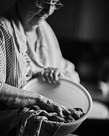 Monochrome portrait of an elderly woman washing clothes in a basin, captured by Annie Edmonds in Los Angeles.