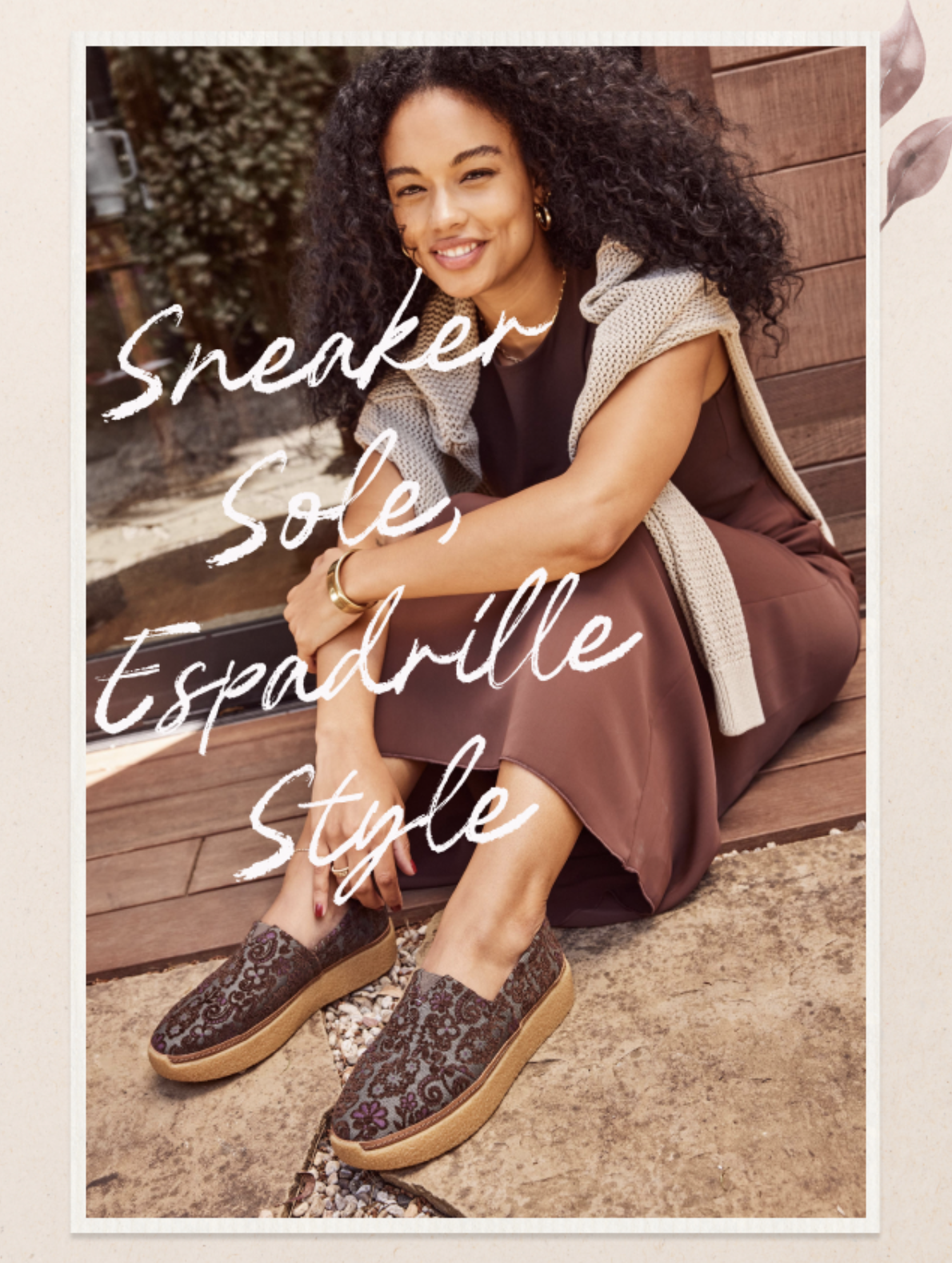 Woman wearing a brown dress and patterned flats sits on a wooden surface; sunlight illuminates her face and casual outfit.