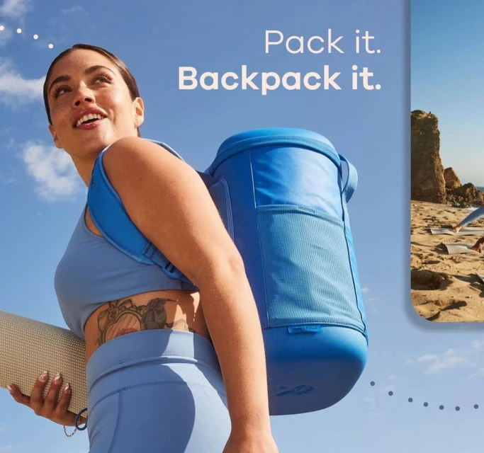 A woman in activewear carries a blue cooler backpack and a yoga mat outdoors with a beach scene visible in a frame on the right.