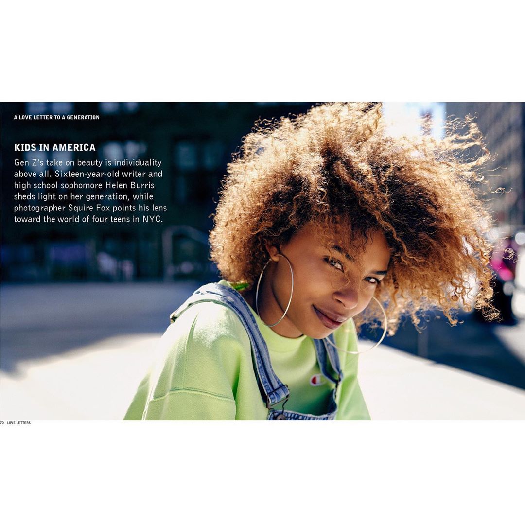 Close-up portrait of a teenage girl with curly hair and large hoop earrings wearing a lime green sweatshirt and denim overalls outdoors in NYC.