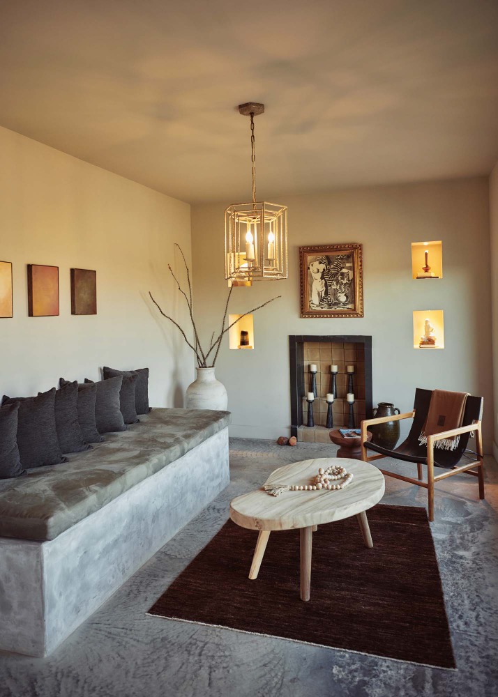 Living room interior with a modern sofa, wood table on a brown rug, and decorative art pieces against a cream wall backdrop.