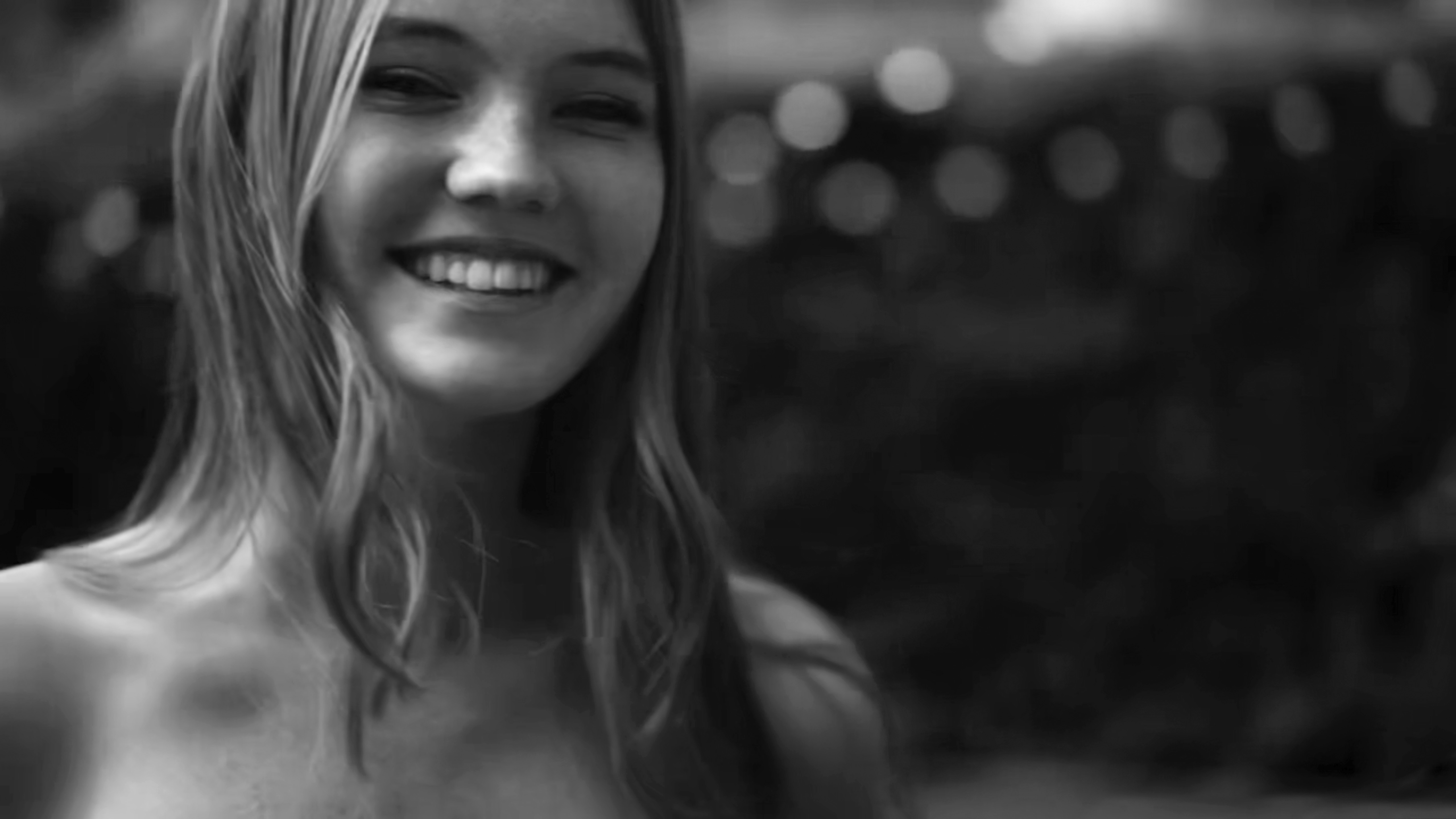 Close-up portrait of a smiling young woman with long blonde hair in a black and white photograph by Squire Fox