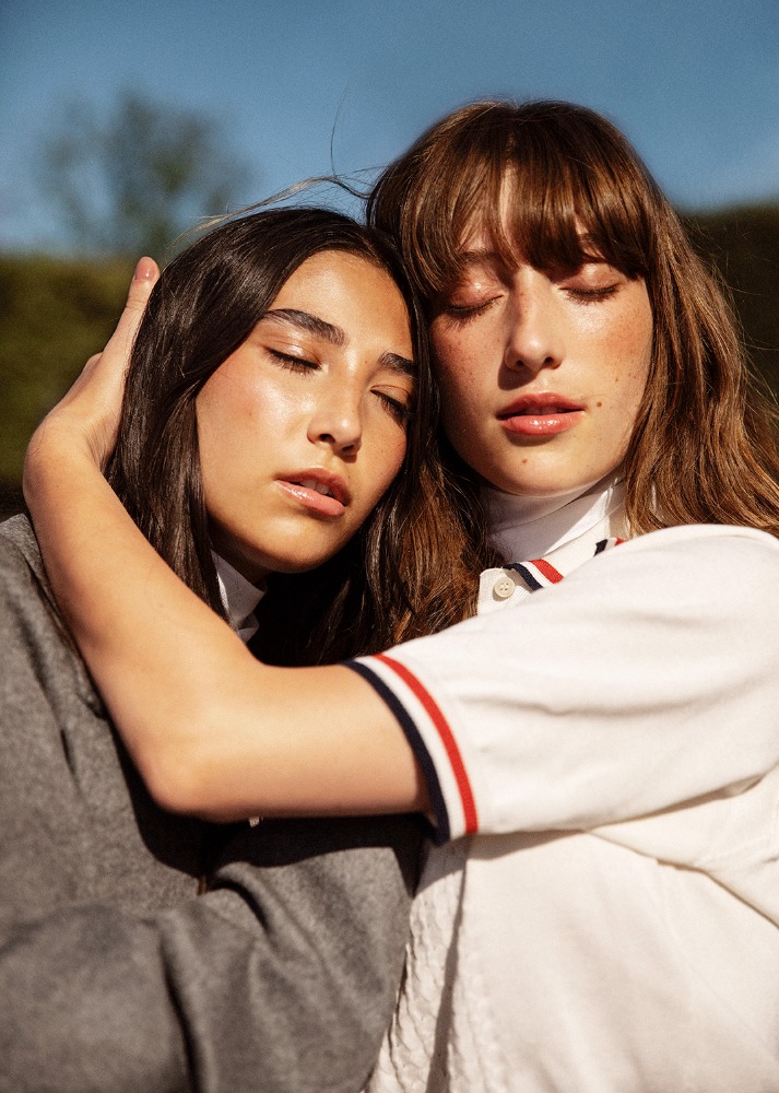 Close-up portrait of two female models with eyes closed embracing under bright natural sunlight by Silja Magg