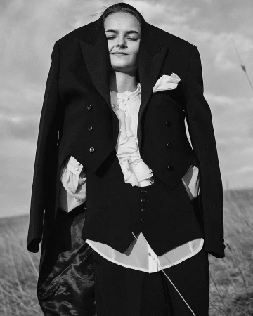 Model wearing an oversized black suit jacket over her head and shoulders, photographed outdoors by Silja Magg.