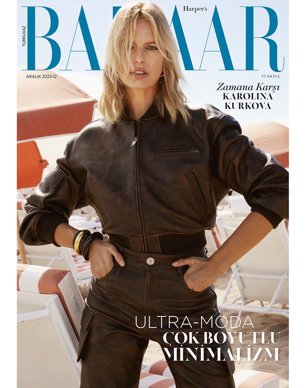 Bazaar Turkey magazine cover featuring Karolina Kurkova, in brown leather jacket and pants, on a beach with white lounge chairs.