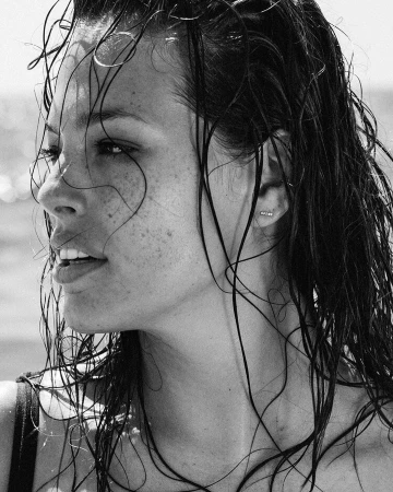 Close up portrait of a woman with wet hair and freckles in black and white photography by Silja Magg