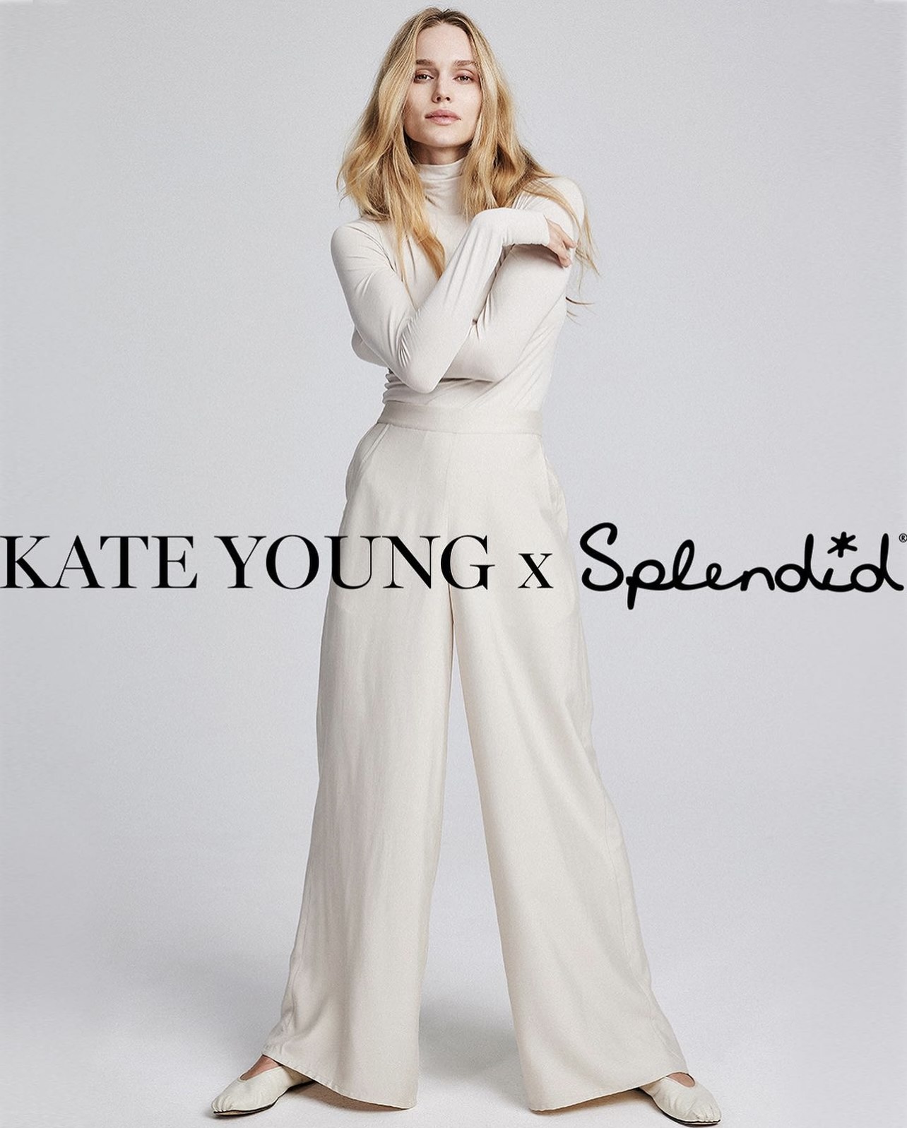 Fashion shot of a blonde adult female model wearing a long-sleeve cream-colored top and wide-leg pants on a light neutral background.