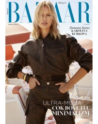 Karolina Kurkova wearing a brown leather bomber jacket and matching trousers on a sunny beach setting