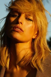 Close-up portrait of a woman with blonde hair and winged eyeliner in golden hour light by Silja Magg