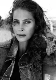 Monochrome portrait of a woman wearing a denim jacket with tousled dark hair outdoors