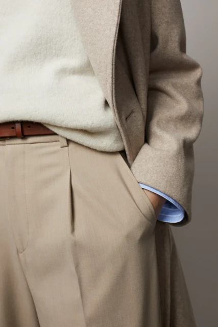 Beige wool coat with a light-colored sweater, brown belt, and beige slacks, demonstrating a sophisticated and neutral color palette.