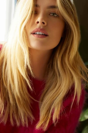 Close-up portrait of a woman with long blonde hair and a red sweater by Caitlin Mitchell