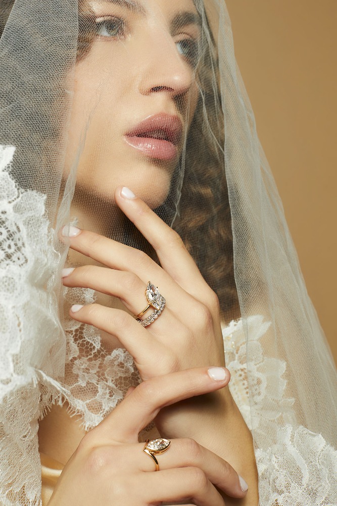 Close-up portrait of a woman wearing a sheer lace veil and diamond rings photographed by Caitlin Mitchell.