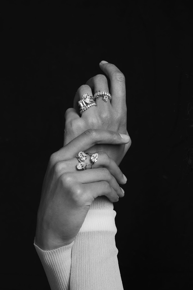 Close-up shot of a person's hands adorned with multiple rings with gemstones, against a dark background, creating a luxurious feel.