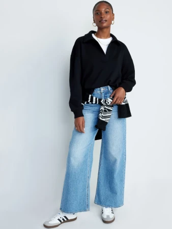 Black long-sleeve collared shirt worn with light blue wide-leg jeans and sneakers against a plain white background.