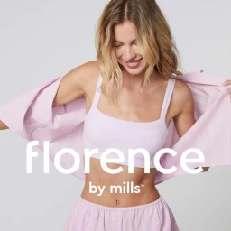 Blonde woman wearing a pink crop top and matching shorts while holding open a striped shirt against a plain background