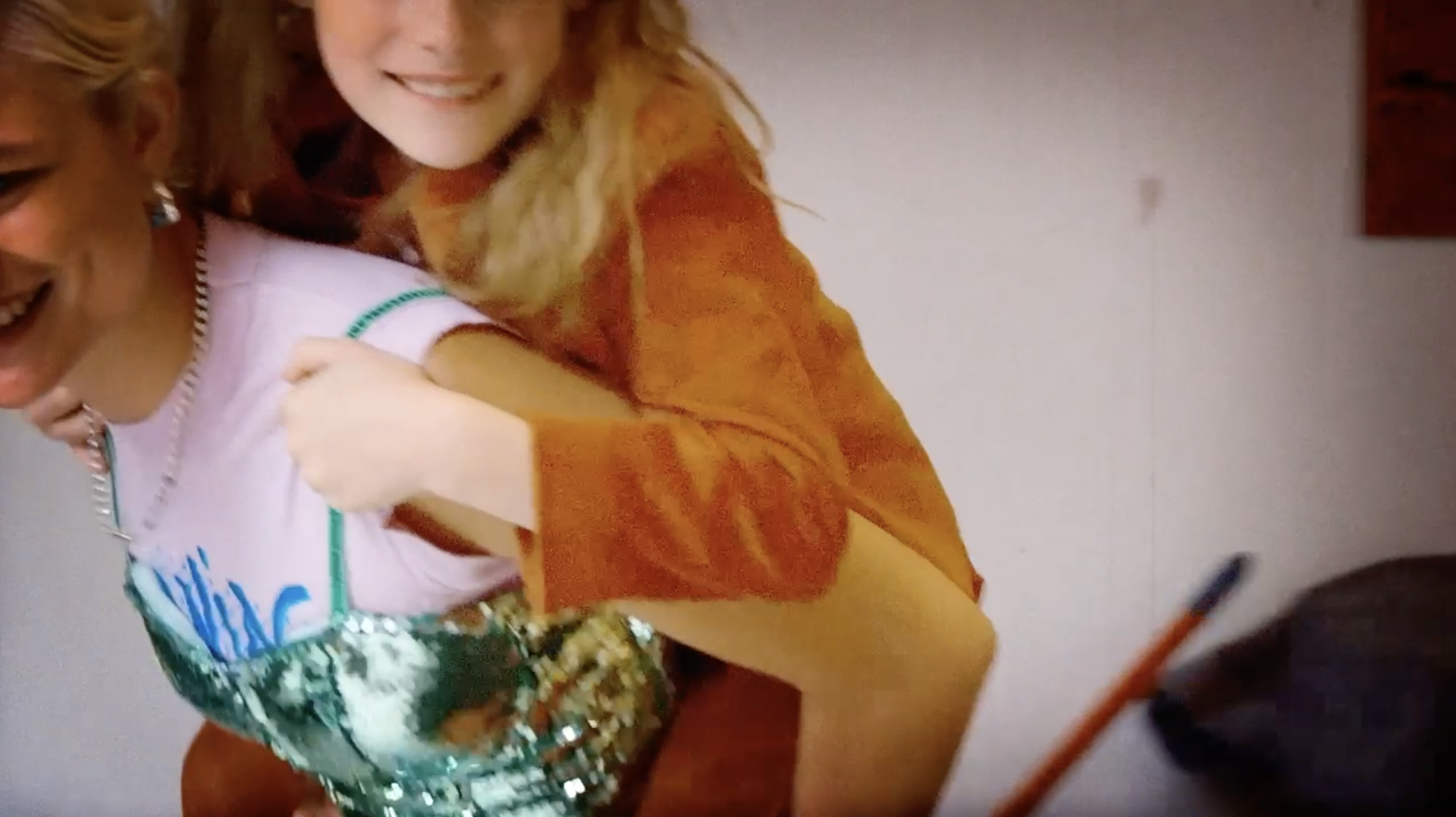 Two smiling women playing together with one giving the other a piggyback ride indoors.