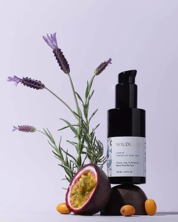 Product shot of Wildlight Lemon Three-In-One Oil with lavender, passion fruit, and kumquats on a gradient white to light purple background.
