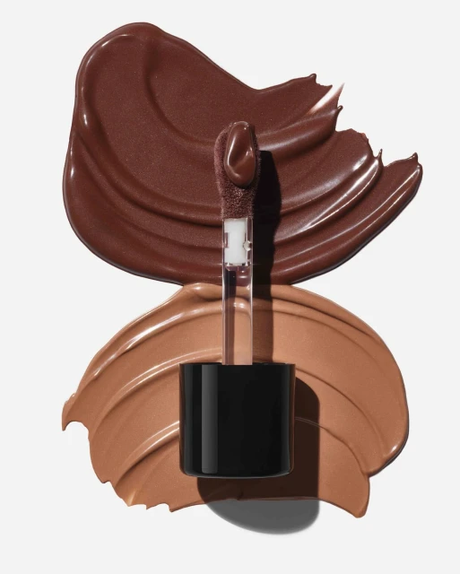 Close-up of two shades of liquid lipstick with applicator, brown and tan, swatched on a white background. Beauty and cosmetics.