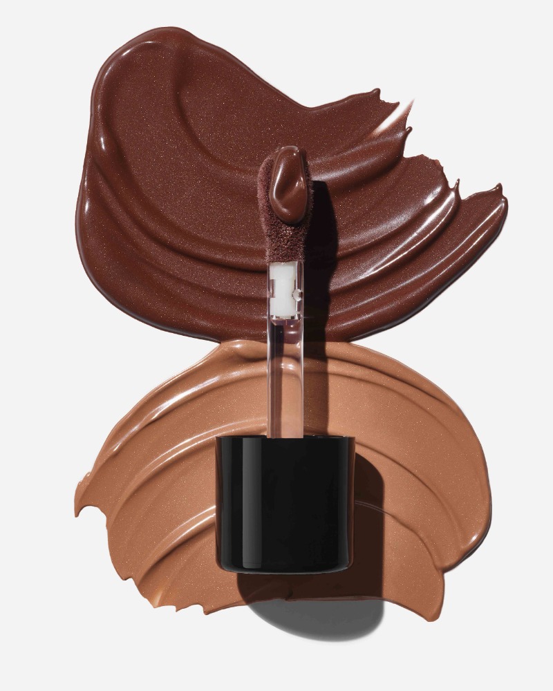 Close-up shot of two different shades of liquid makeup or cosmetic foundation, displayed on a white background with product applicator.