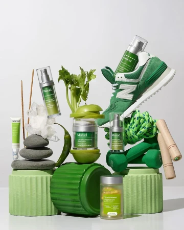 Still life featuring Murad skincare products with exercise equipment and produce, all arranged on green pedestals against a white background.