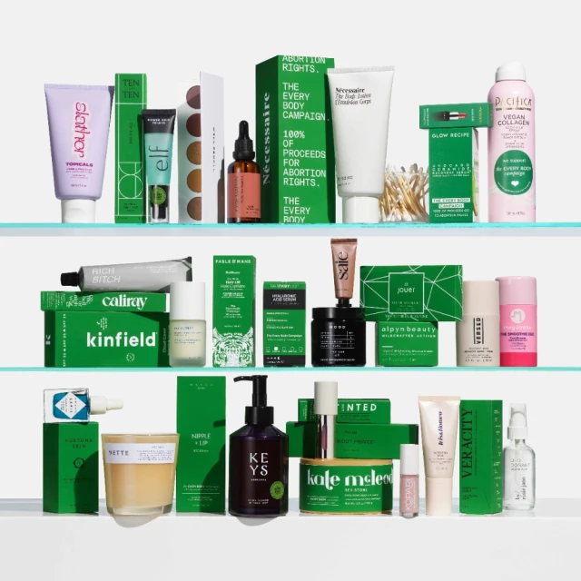 Collection of skincare and cosmetic products on clear shelves, including creams, serums, and cleansing products in green and neutral packaging.