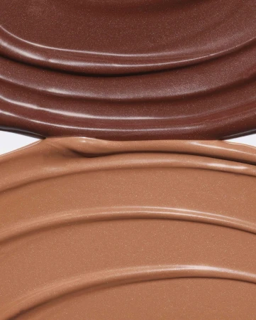 Close-up macro view of smooth brown cosmetic liquid cream swatches with glossy ridges against a plain background
