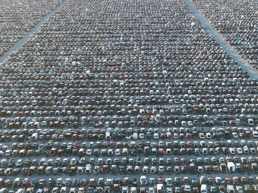 Extensive aerial view of a vast car junkyard filled with thousands of vehicles, showcasing automotive waste and recycling landscape.