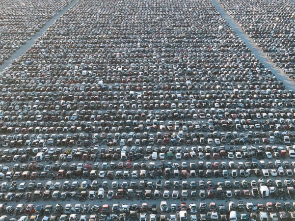 Extensive aerial view of a vast car junkyard filled with thousands of vehicles, showcasing automotive waste and recycling landscape.