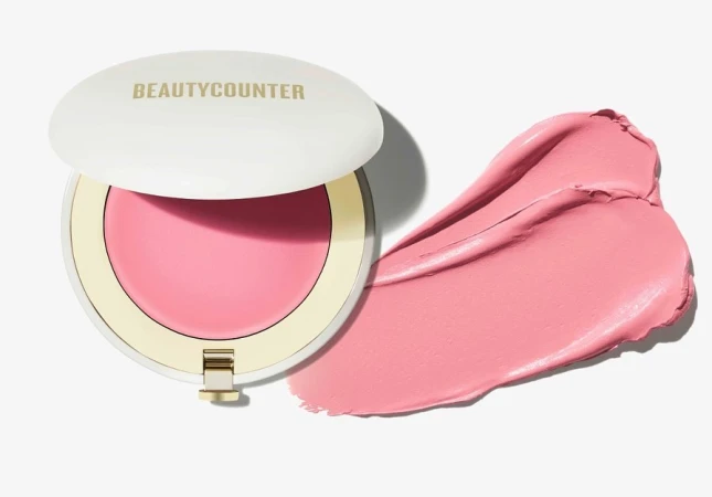 Beautycounter cream blush compact with blush swatch on a white background. Cosmetic product shot for beauty and makeup.