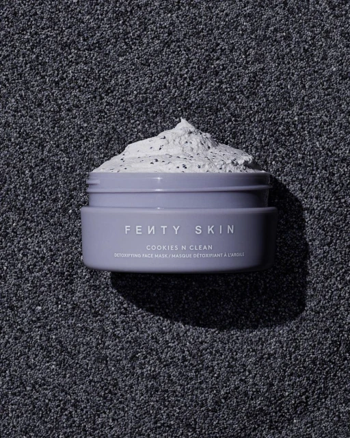 Close-up of Fenty Skin Cookies N Clean detoxifying face mask in a lavender jar on a textured dark grey background.