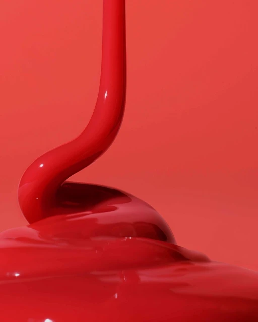Bold, shiny red liquid is captured in a close-up studio shot with a vibrant, monochromatic red backdrop, showcasing texture and movement.
