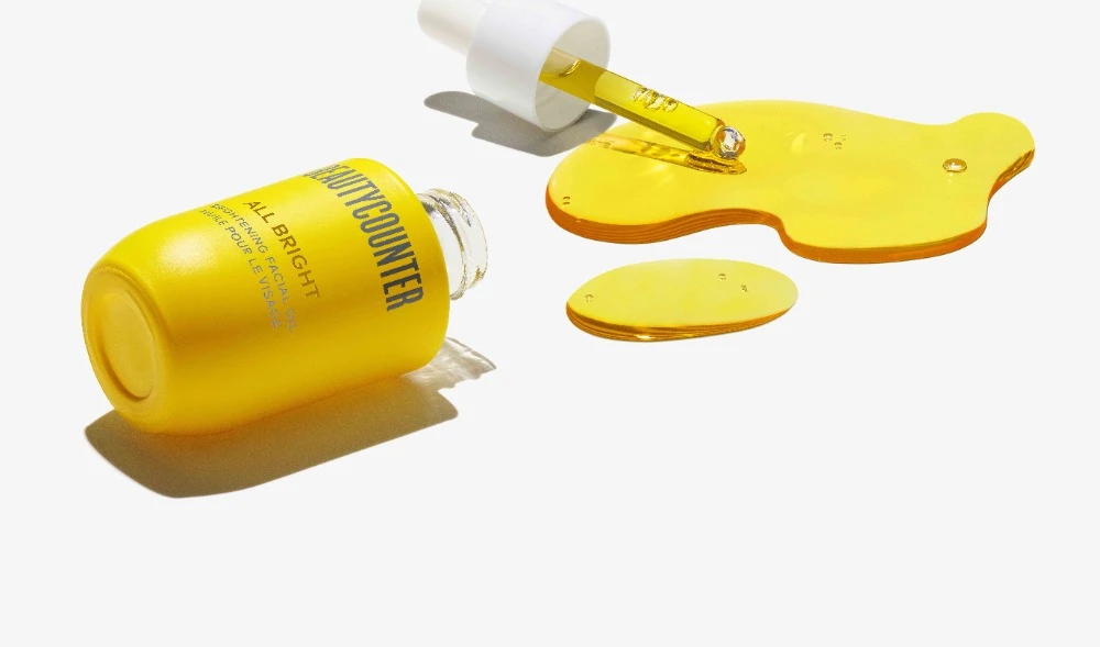Beautycounter All Bright serum product shot on white background. Yellow liquid and bottle with white dropper, beauty photography.