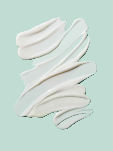 Close-up of thick, creamy white beauty product swirls diagonally across a light blue background, ideal for cosmetic promotions.