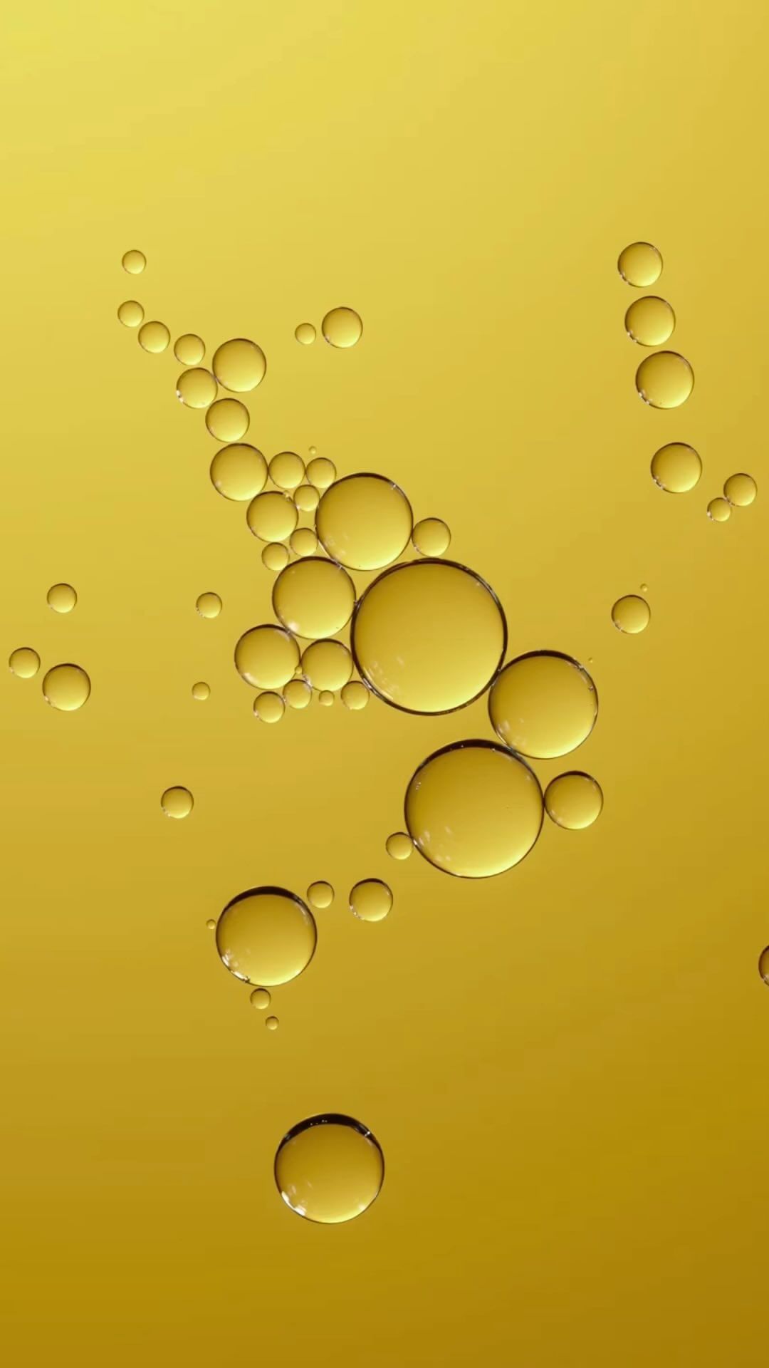Close-up of golden yellow liquid featuring a collection of transparent spheres, varying in size, against a gradient background.