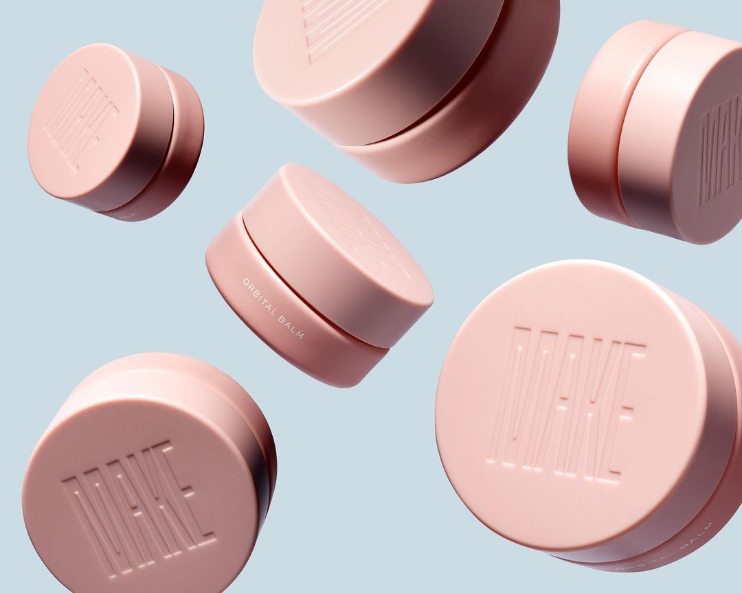 Multiple pink cosmetic jars floating in the air against a light blue backdrop, showcasing beauty and skincare products.