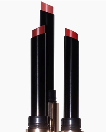Close-up of three lipstick tubes with red shades against a white background. Beauty product photography.