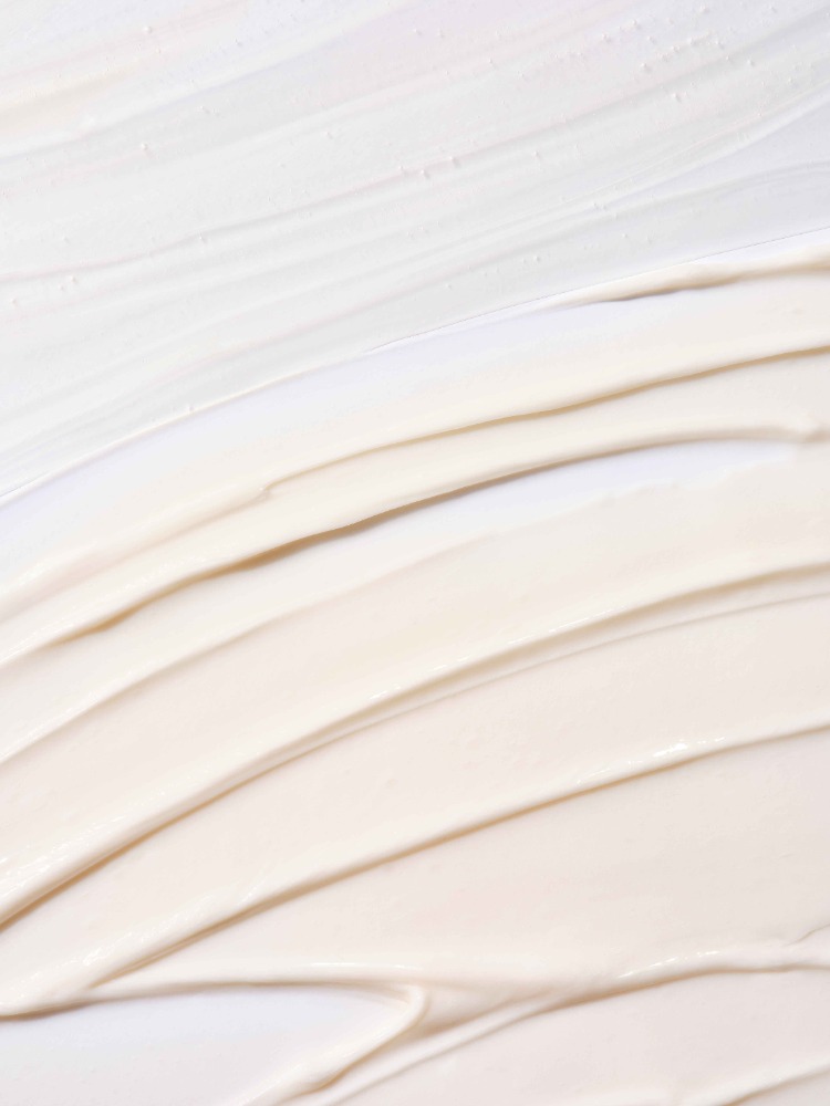Close-up of cosmetic cream texture, showing thick beige and white swirls, ideal for beauty or skincare product advertising.