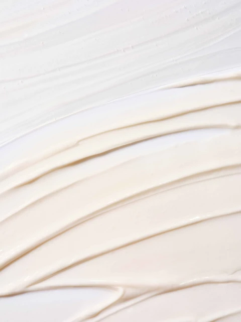 Close-up of cosmetic cream texture, showing thick beige and white swirls, ideal for beauty or skincare product advertising.