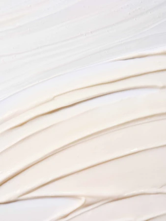 Close-up of cosmetic cream texture, showing thick beige and white swirls, ideal for beauty or skincare product advertising.