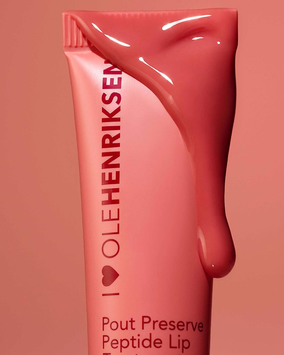 Close-up of pink Ole Henriksen lip treatment tube with product, against a matching pink background. Beauty and skincare product.
