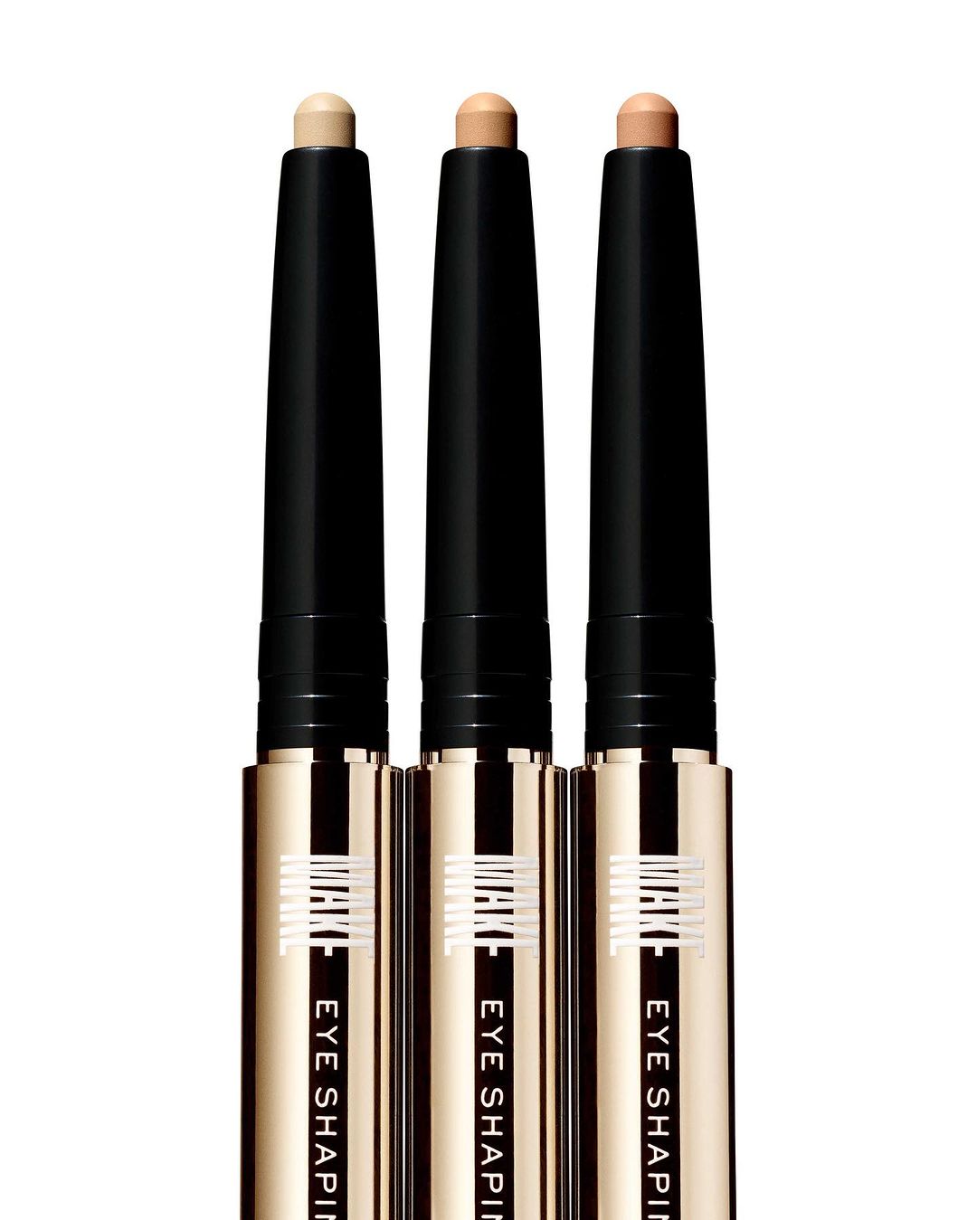 Three eye shaping sticks in a row, featuring black and gold packaging with cream-colored product, against a white background.