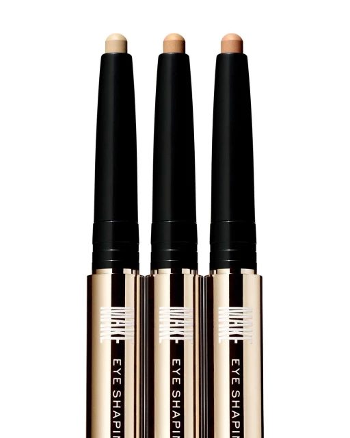 Three eye shaping sticks in a row, featuring black and gold packaging with cream-colored product, against a white background.