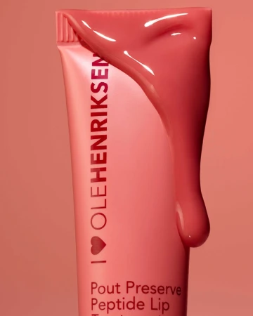 Close-up of a pink Ole Henriksen Pout Preserve Peptide Lip Treatment tube with lip treatment dripping down the side on a pink background.