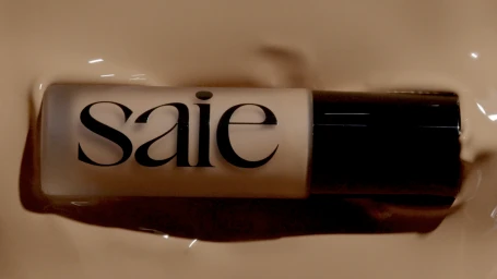 Saie cosmetics liquid foundation bottle submerged in liquid beige foundation cream texture