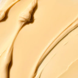Close-up macro shot of smooth beige cosmetic cream texture swatched across a flat surface.
