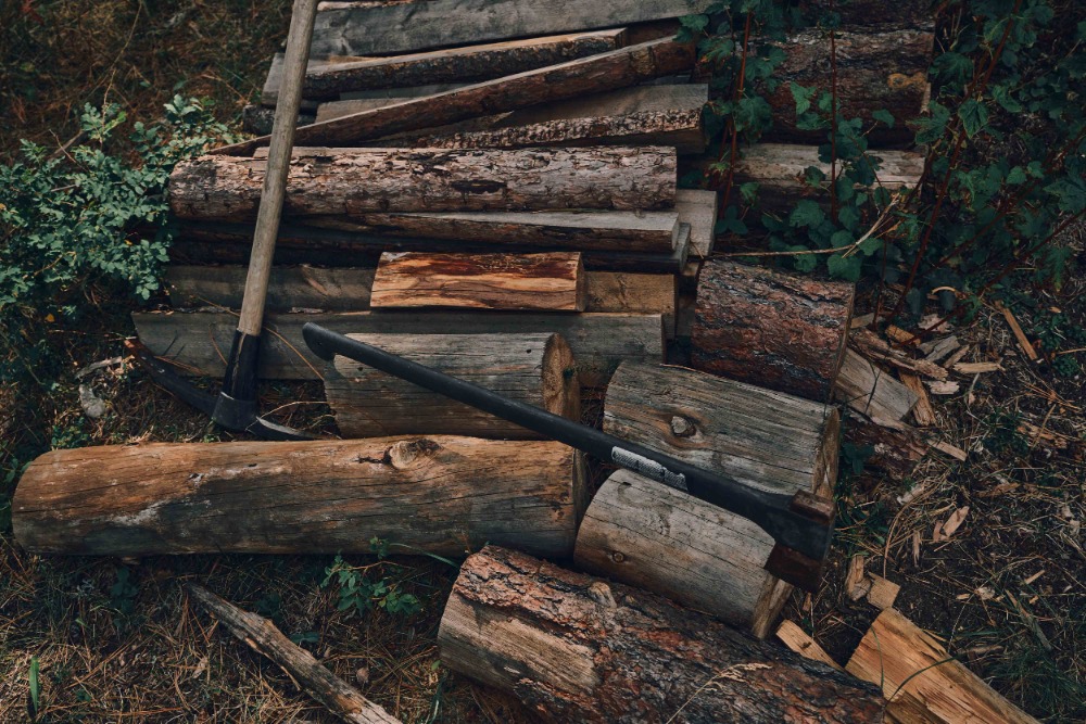 Stacked firewood and axe in a forest environment. Close-up of split logs for burning with an axe, creating a warm, rustic, natural vibe.