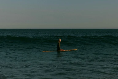 Surfer on a longboard sitting on the ocean waters, photographed in Los Angeles by John Schell.