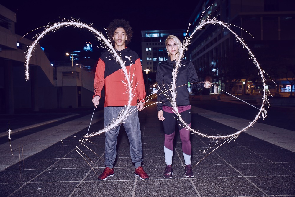 Two models holding sparklers creating glowing light arcs outdoors at night, photographed by Jon Johnson.